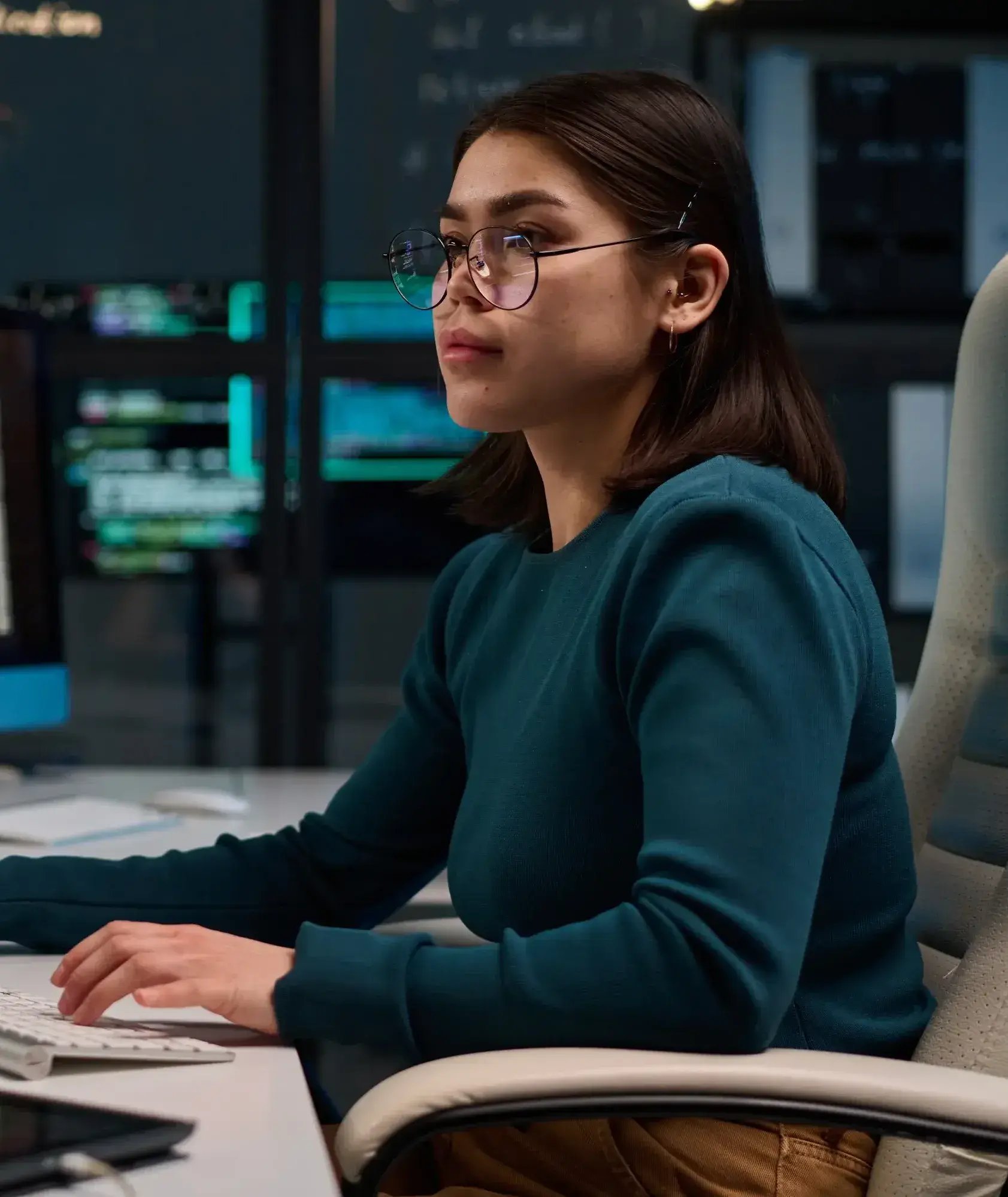 young woman wearing glasses as cybersecurity engineer typing at computer keyboard in a data center-1