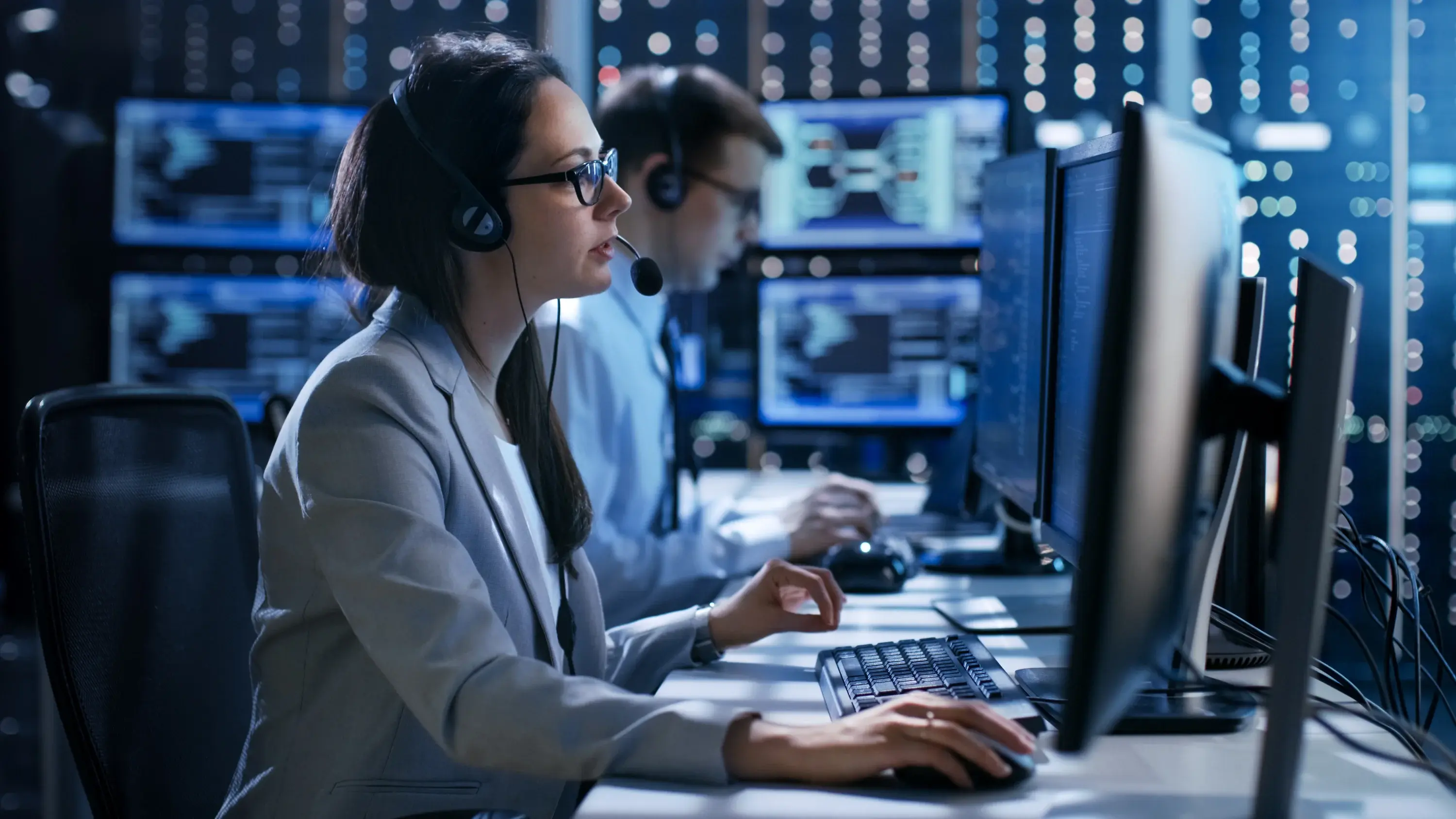 Data support operator with headset helping a customer, with data banks behind